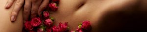 Bauch einer Frau mit Rosen und Hand